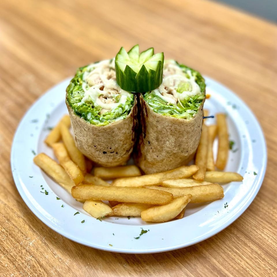 Two Michigan Deli wraps filled with lettuce and sauce, garnished with cucumber, served with fries.